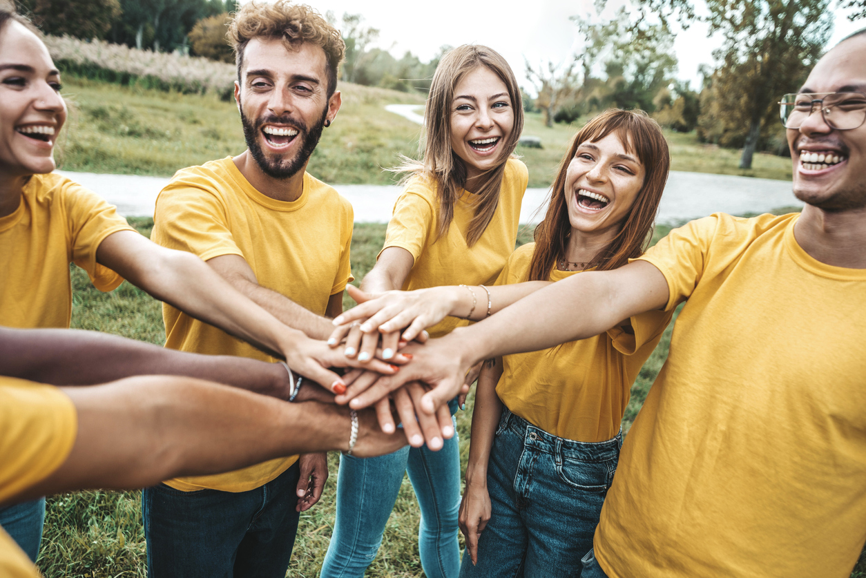 Multi ethnic young people team stacking hands together outside - International university students support and help each other - Friendship, team building, human relationship and diversity concept