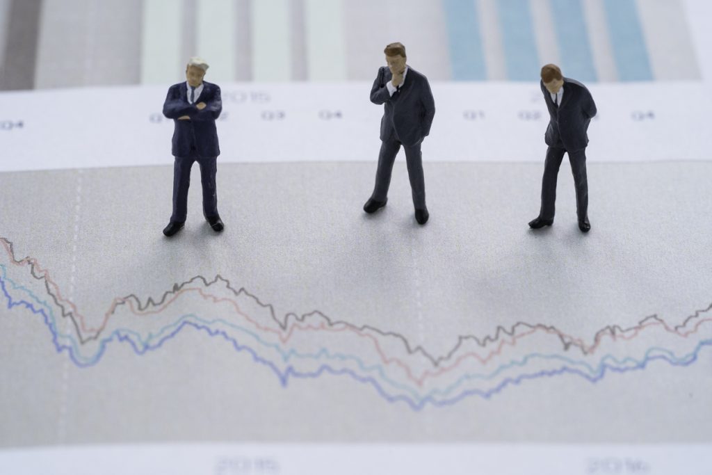 analysis stock market investment concept , three businessman miniature figure standing and analysts stock technical chart.