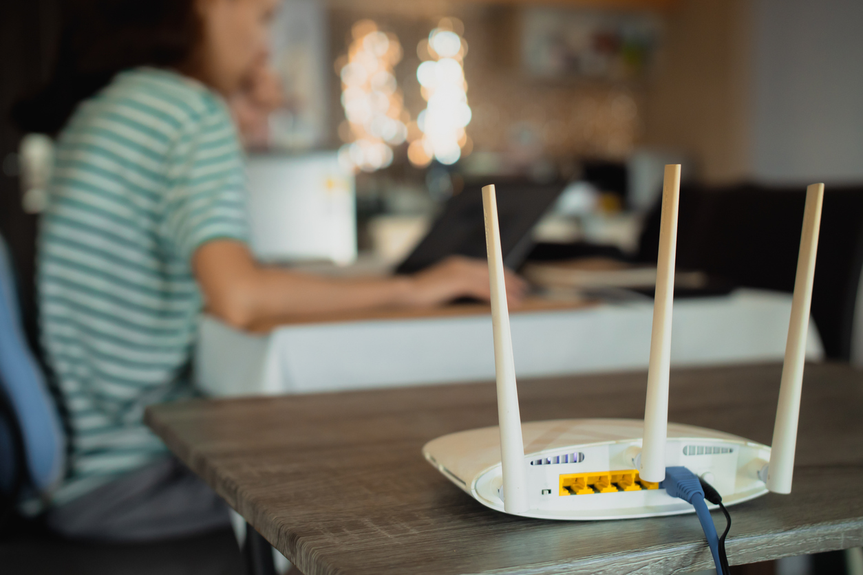 a woman is working at home using a modem router, connecting the internet to her laptop.