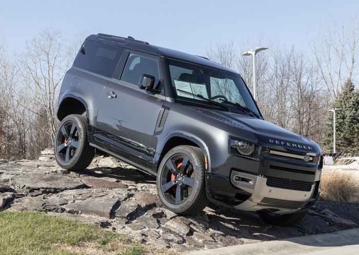 land rover defender display at a dealership. land rover offers the defender in base, se, v8 and carpathian models.