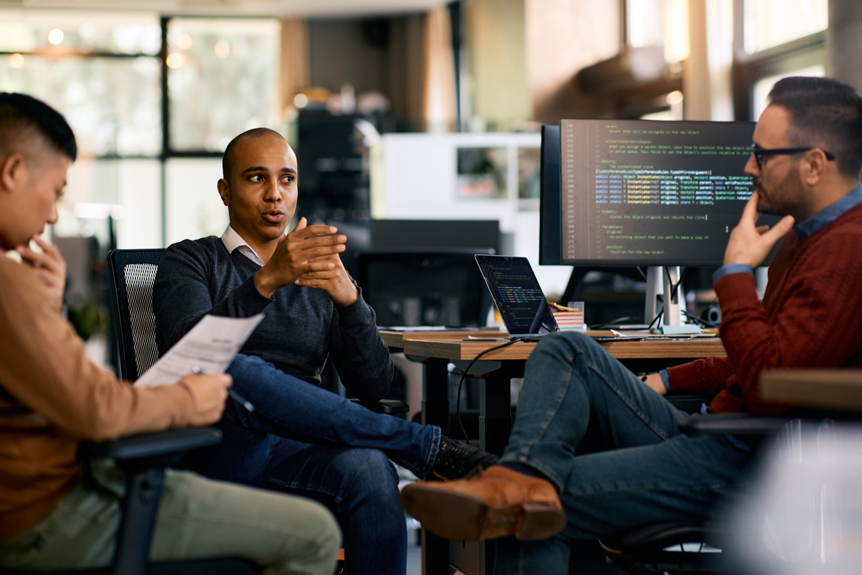 group of computer programmers talking while working at it office.