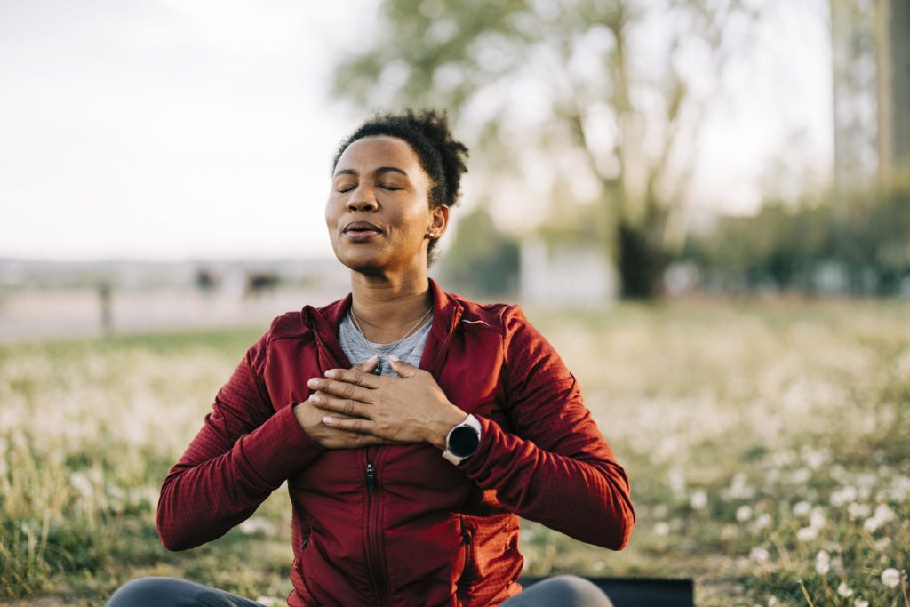 black woman, breath and hand on chest, for meditation and wellness being peaceful to relax. bokeh, african american female and lady outdoor, in nature and being calm for breathing exercise and health