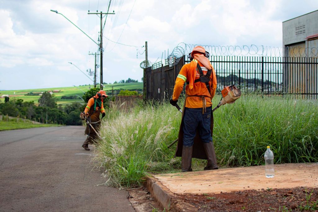Workers Cutting Grasses on the Side of the Road Near Metal Gate