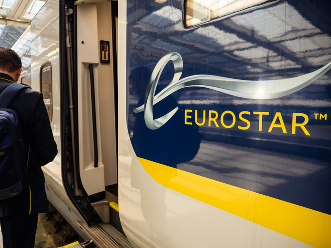 rear view of passenger male with backpack entering the large door of the eurostar train in st parnas train station with estination paris france