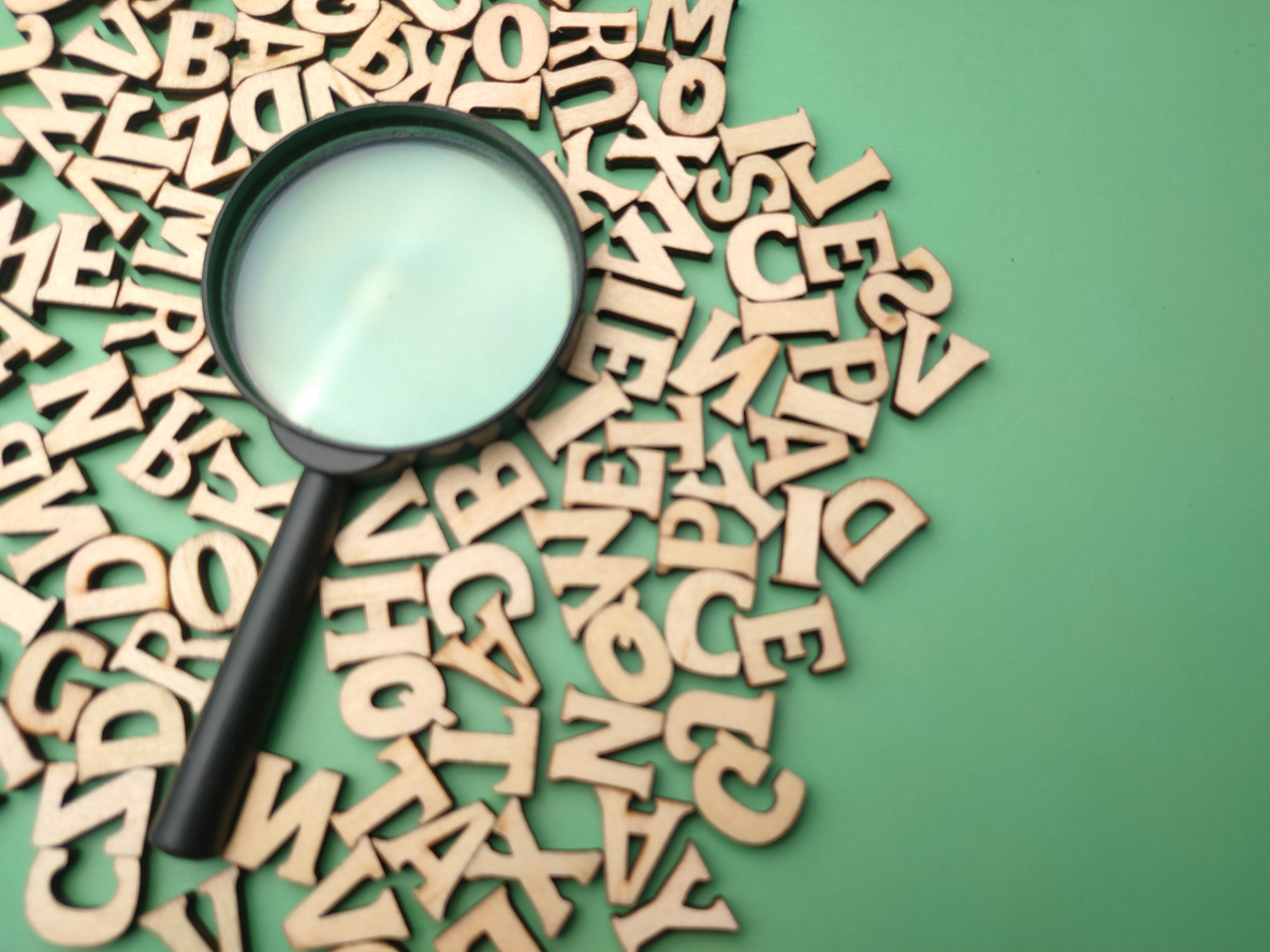 wooden word and magnifying glass on a green background
