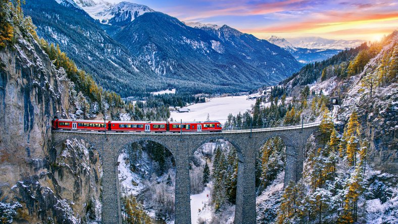 aerial view of train passing through famous mountain in filisur, switzerland. landwasser viaduct world heritage with train express in swiss alps snow winter scenery.