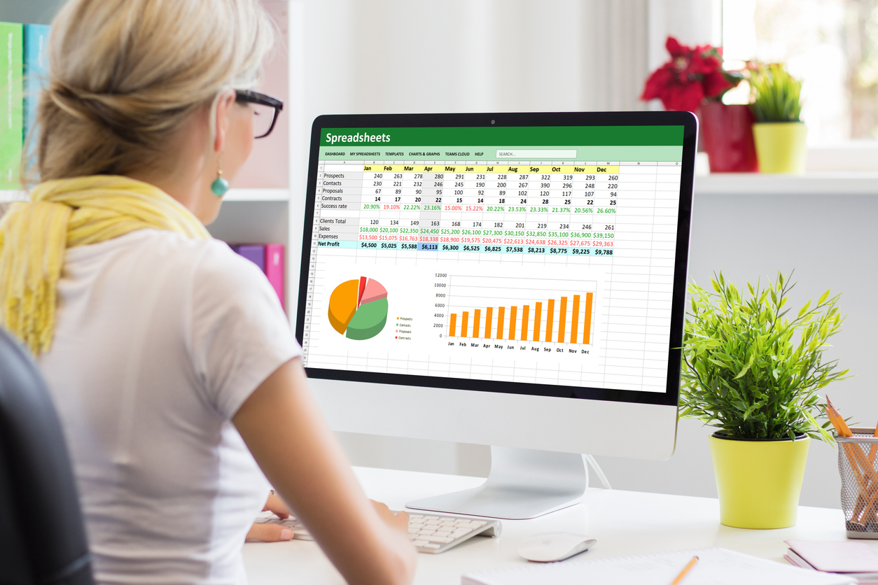 woman working with data and graphs in spreadsheet document on desktop computer