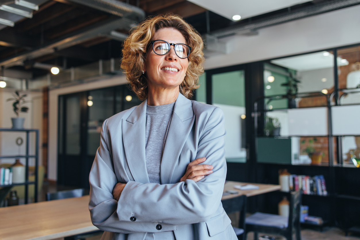 business woman in her 40's looks away thoughtfully in an office