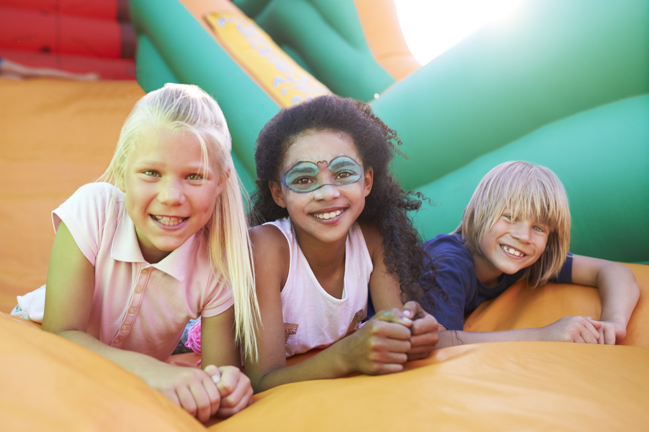 portrait of children on inflatable slide at summer garden fete