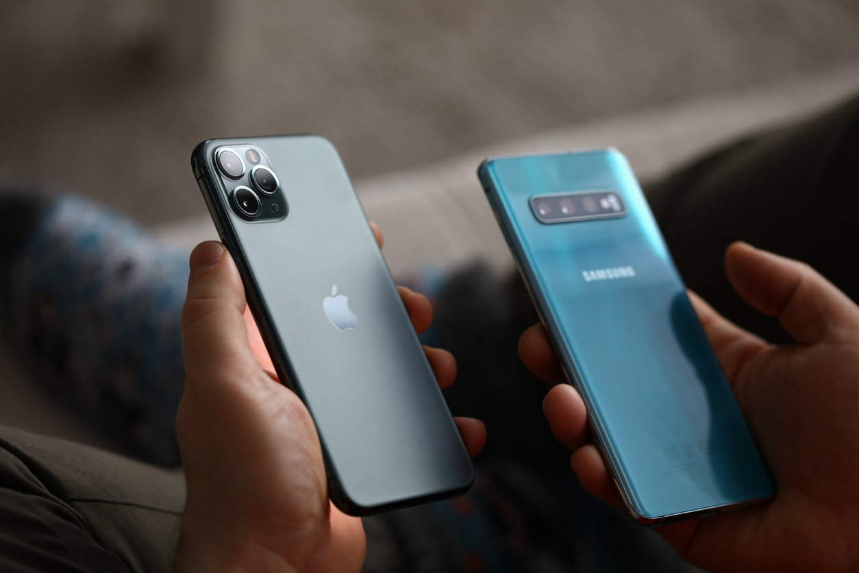 male hand hold apple iphone pro and samsung galaxy s 10