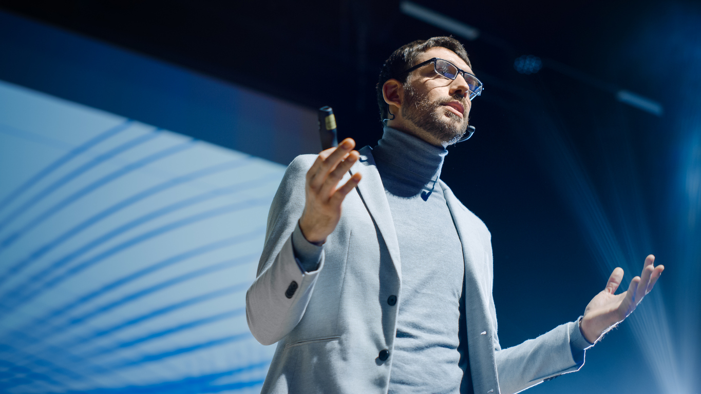 portrait of inspirational innovative speaker, talking about happiness, self, success, empowerment, efficiency and how to be more productive self. large conference hall with cinematographic light