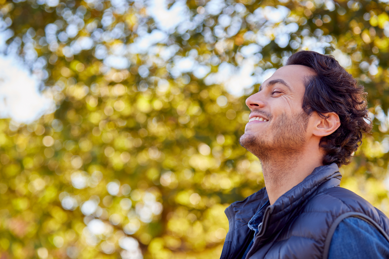 calm man outdoors relaxing and breathing in deeply in autumn park