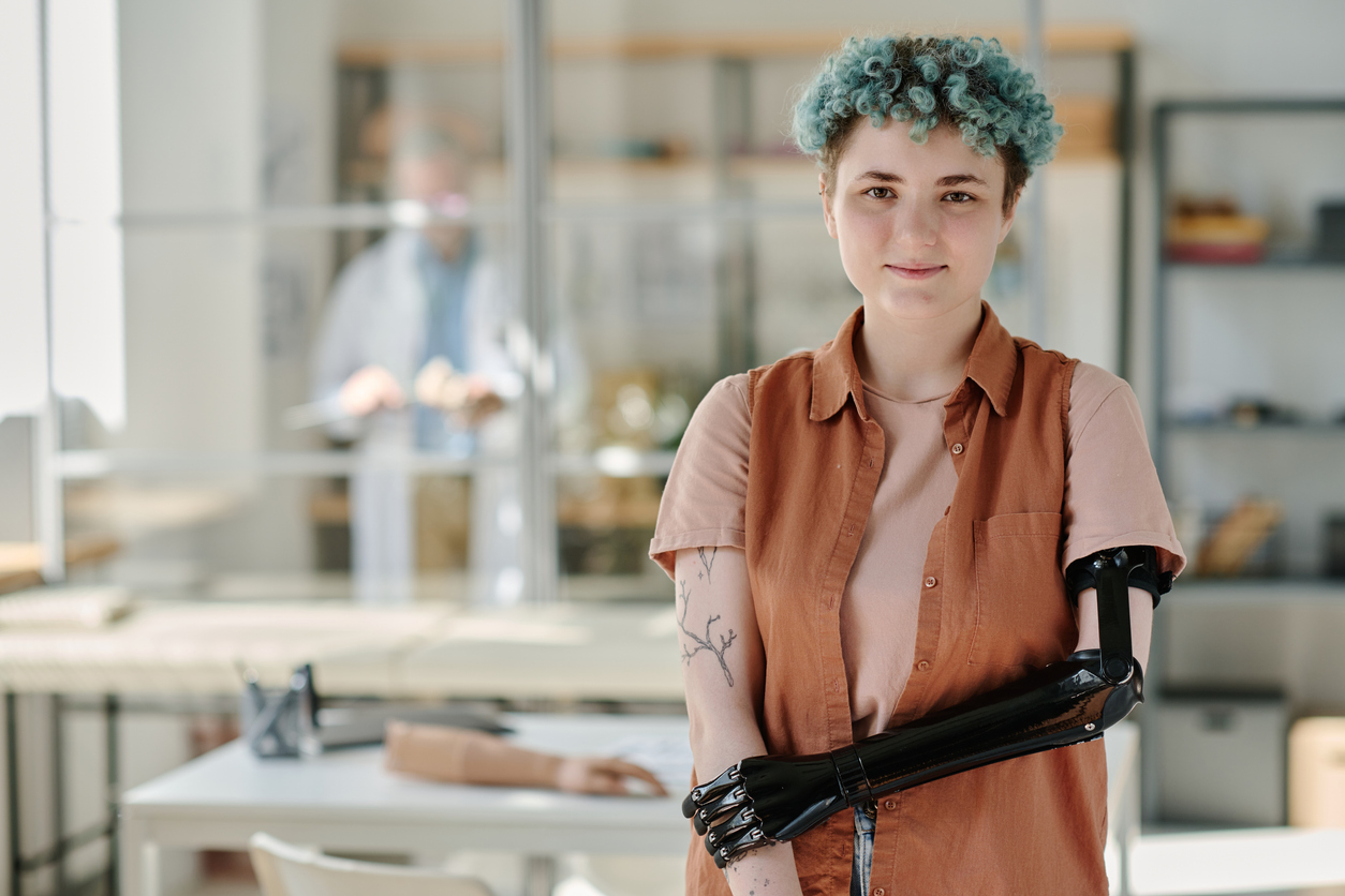 young woman with bionic prosthetic arm smiling at camera