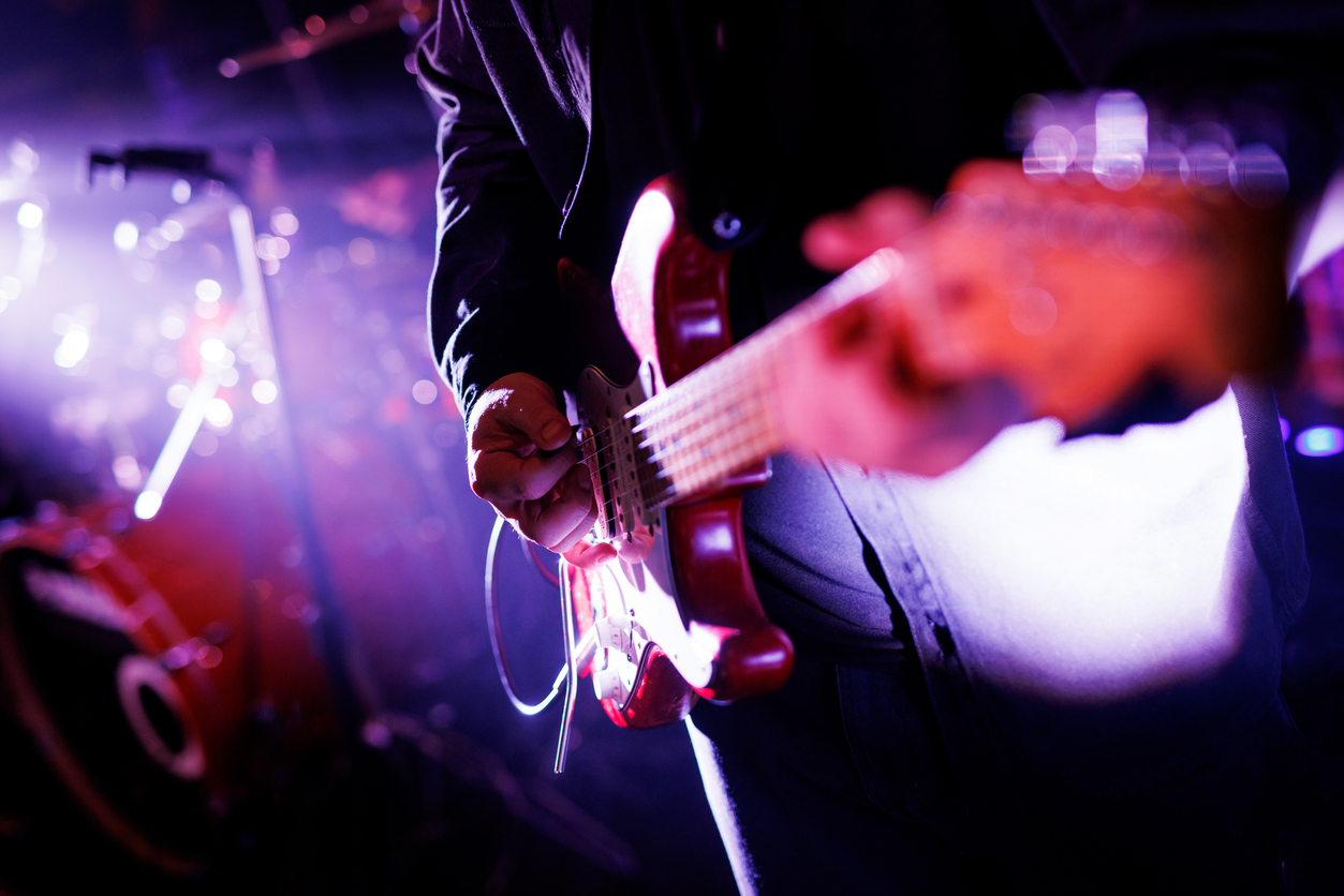 close up of a musician playing the electric guitar during a concert.