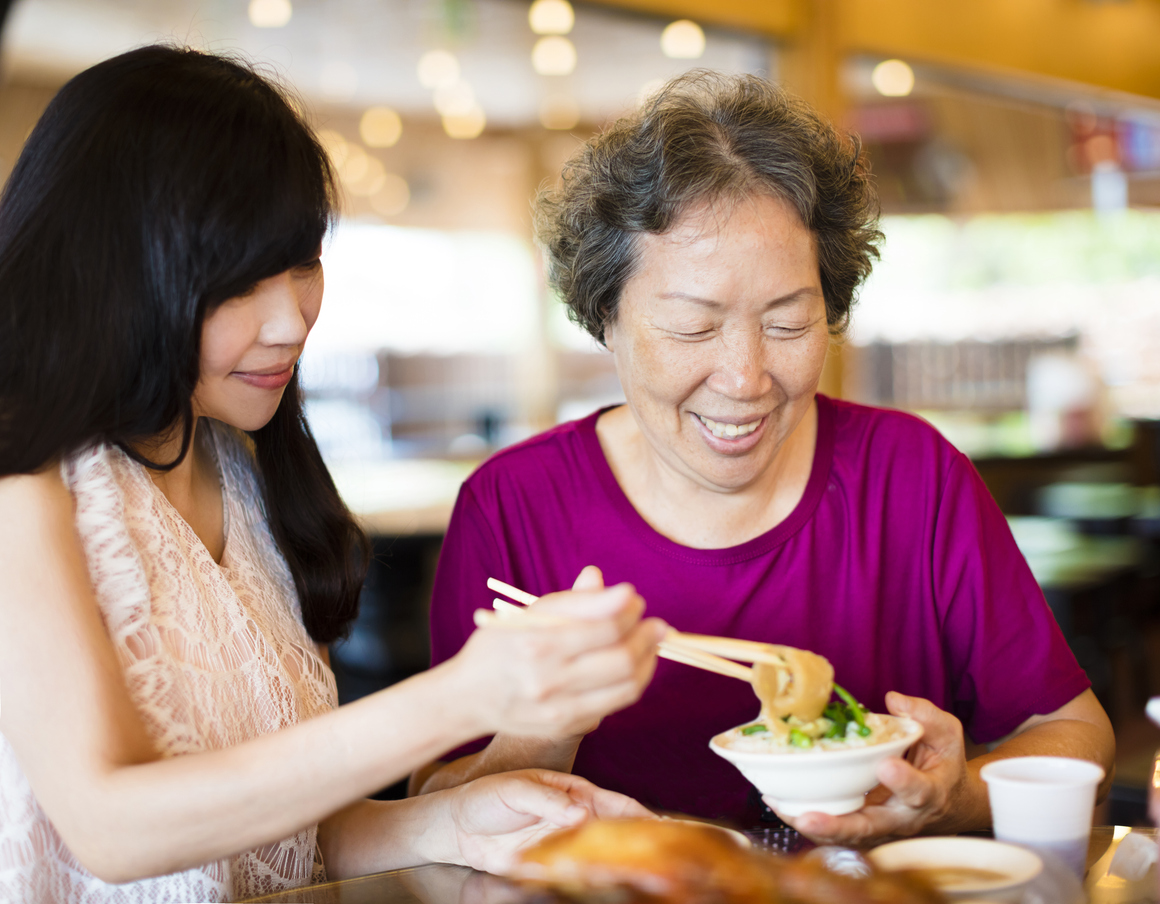 happy daughter and senior mother enjoy eating in restaurant