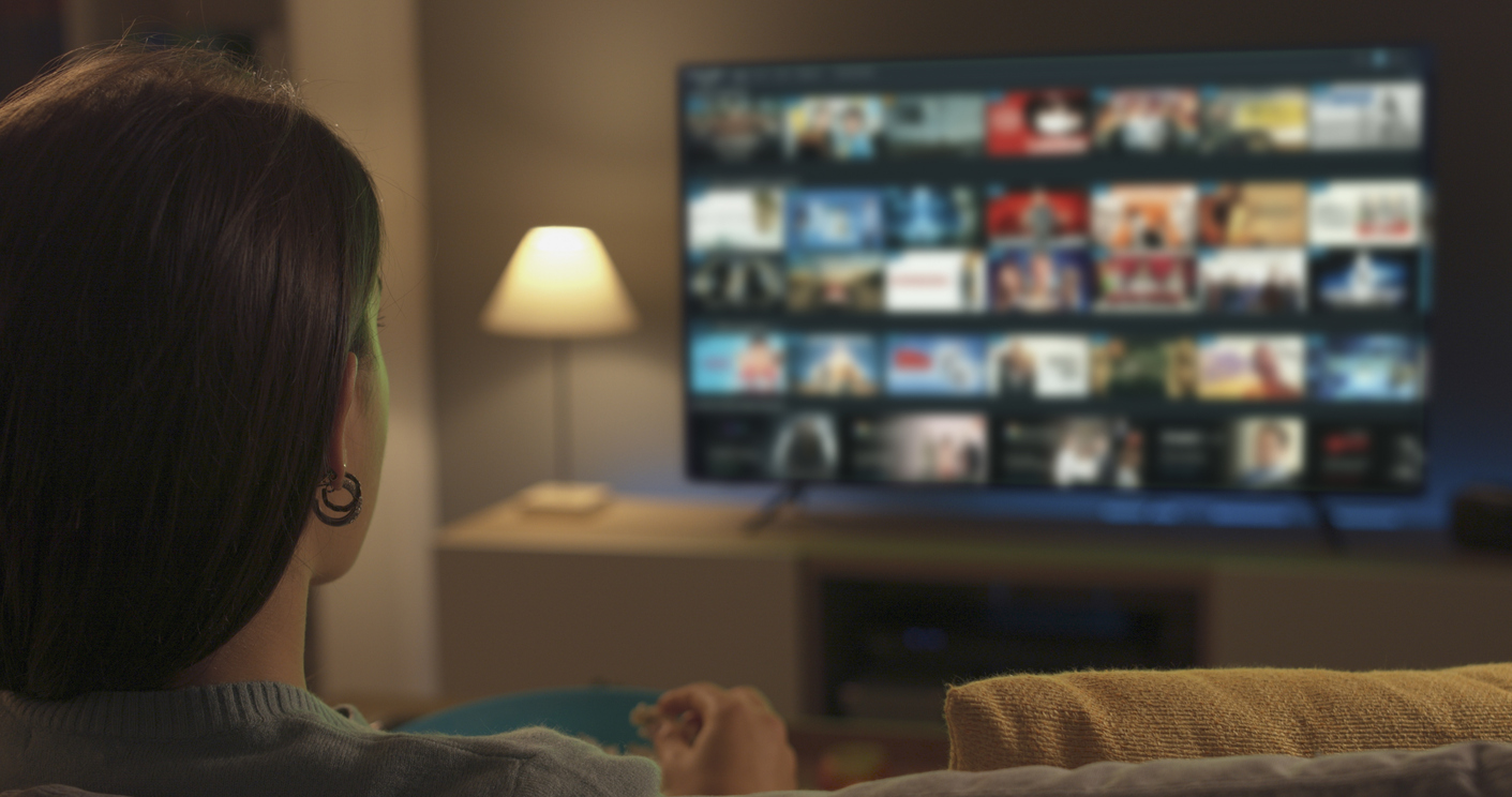 young woman watching video on demand on her tv