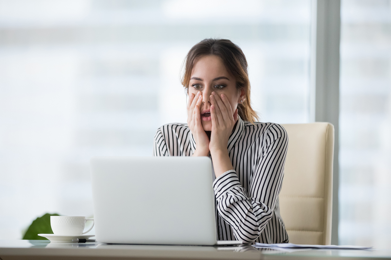 shocked young woman looking at laptop screen.