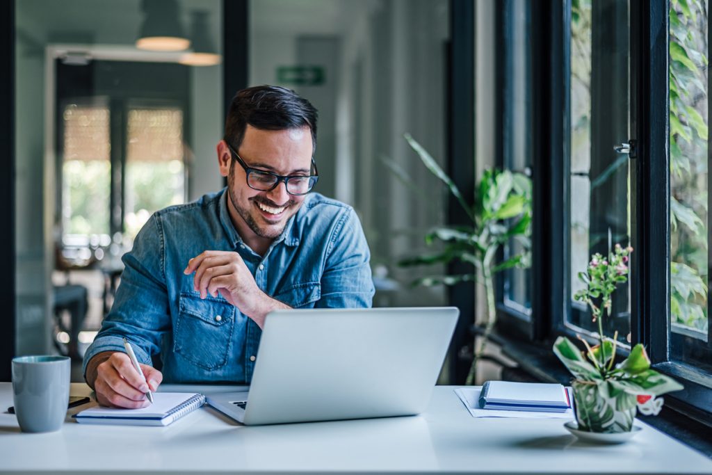 lovely business man, attending a meeting online, writing stuff down.