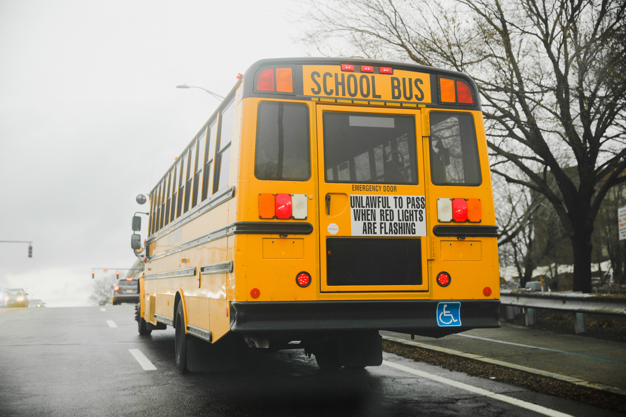 yellow school bus parked on a quiet suburban street. the bus is bright yellow with tinted windows and a stop sign on the side. photo conveys a sense of safety and nostalgia.