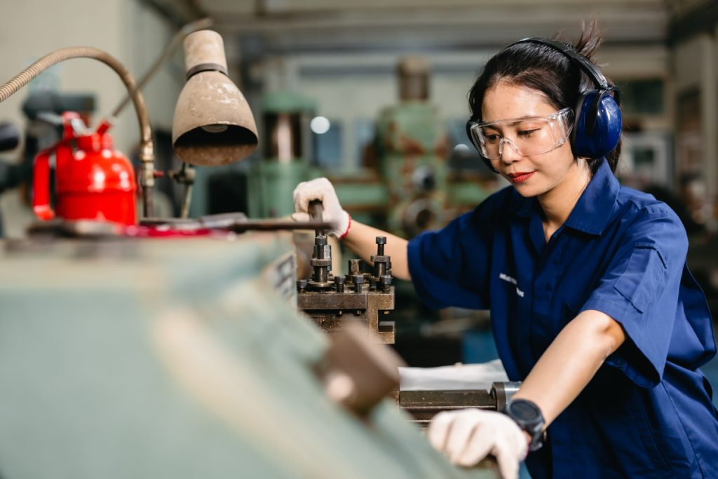 professional engineer worker with safety eyes protection focus working in metal lathe milling machine heavy industry factory.