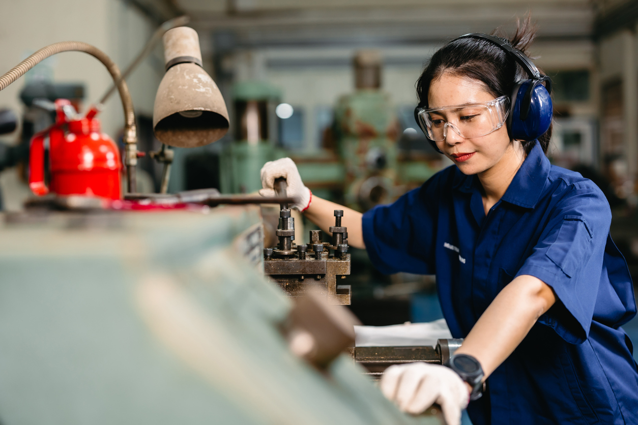 professional engineer worker with safety eyes protection focus working in metal lathe milling machine heavy industry factory.