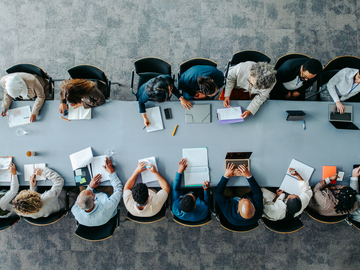 overhead shot of business panel in office meeting collaborating around large table
