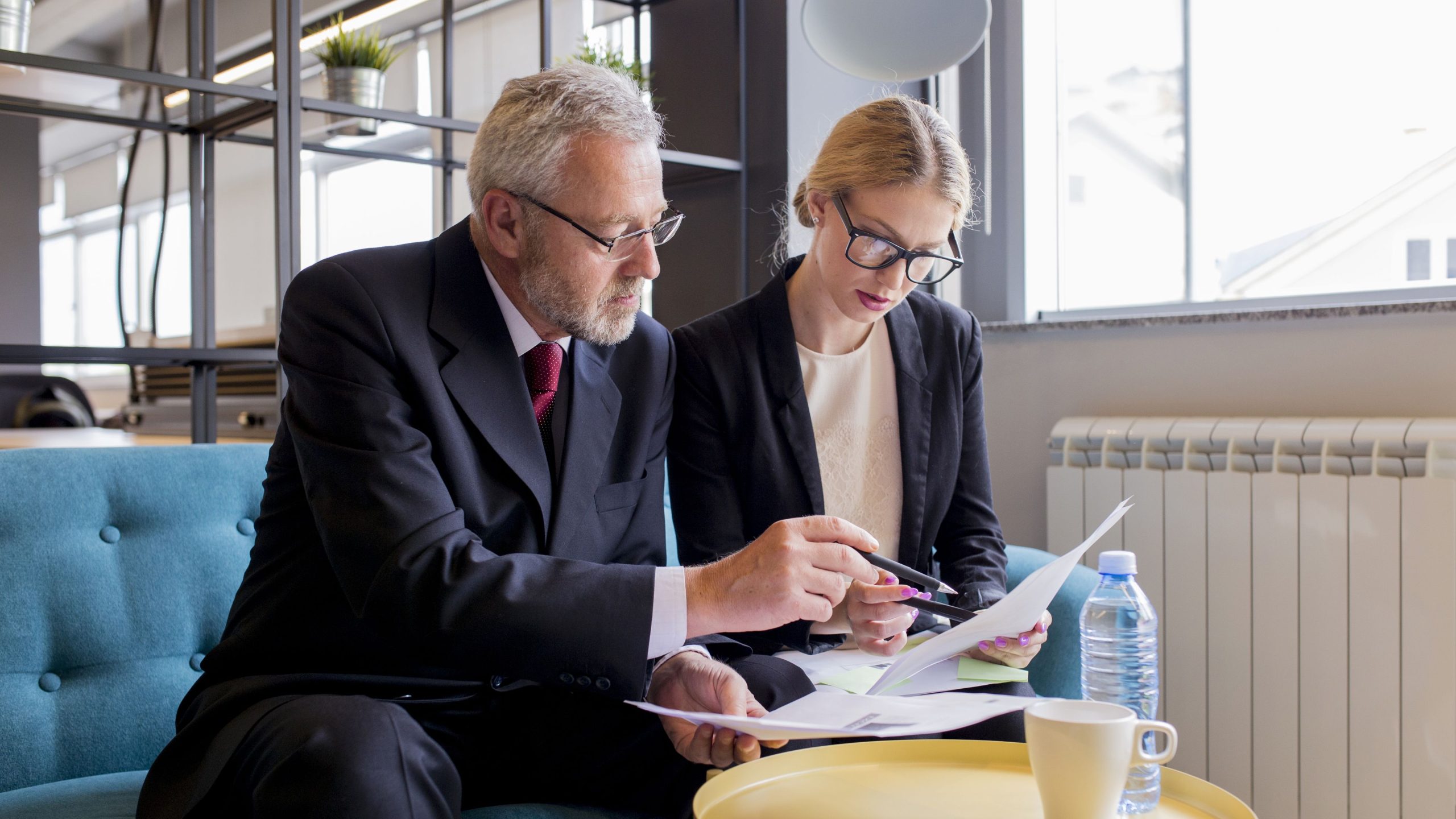 An older businessman and businesswoman reviewing a loan contract for their business.