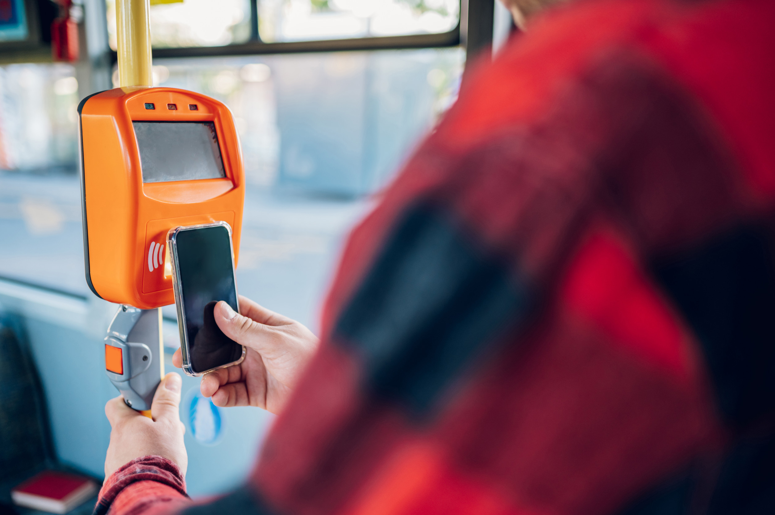 close shot of a man hand holding a smartphone while paying a bus