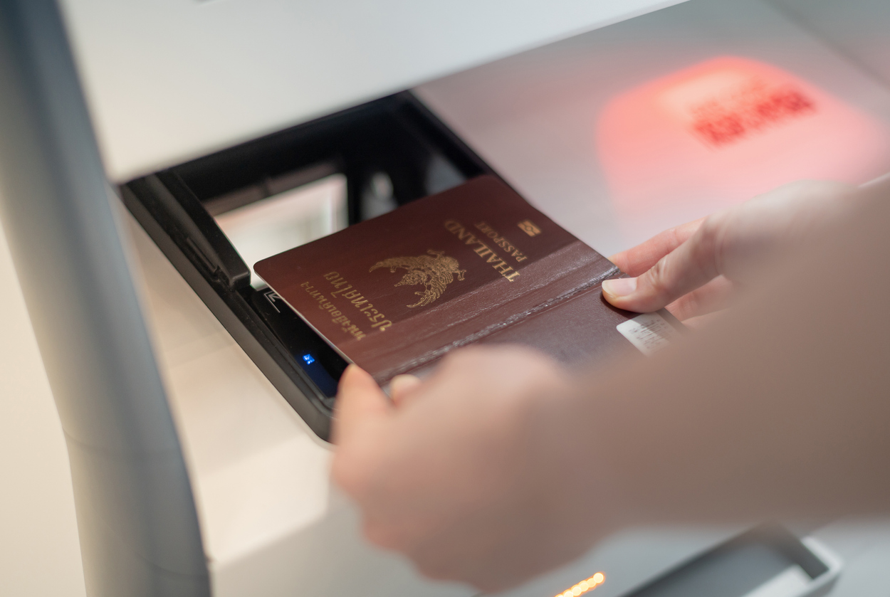 female hand holding personal passport scanning at the self service checkin counter for get boarding pass at the airport terminal.