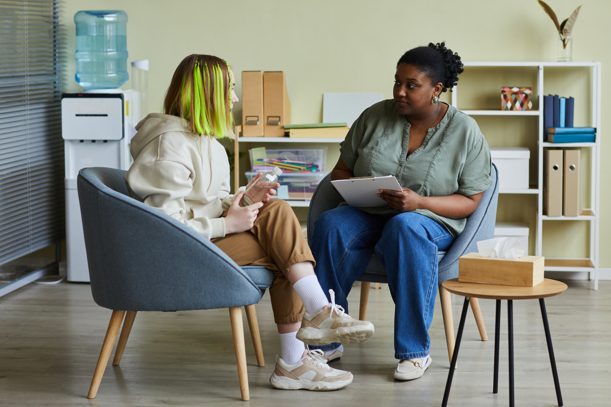 woman social worker talking to teenage girl at office