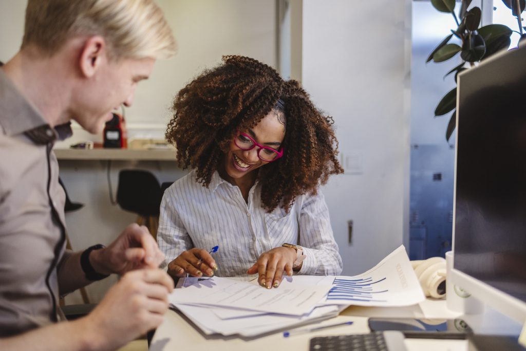 business people working together on project smiling at office desk