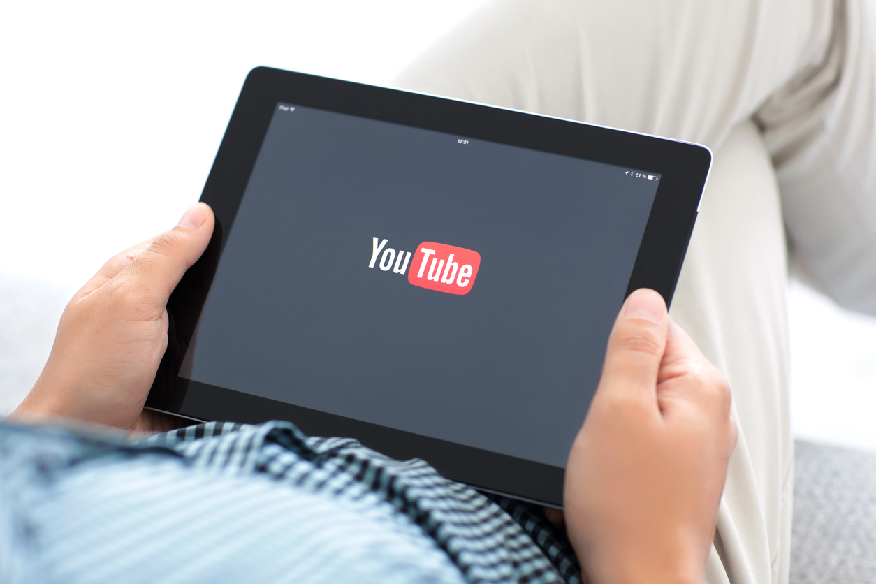 man holding ipad with app youtube on the screen