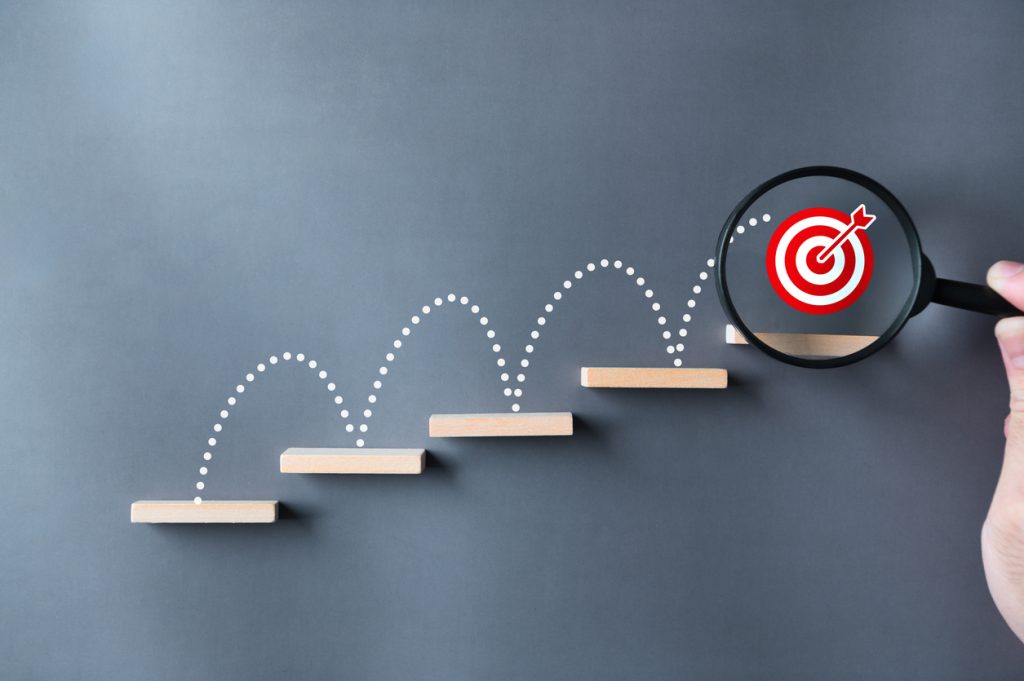 unlock potential of business success stairs dart and dartboard targets magnifying glass with hand on gray background. explore opportunities growth embrace steps to achieve ambitions and goal concept.