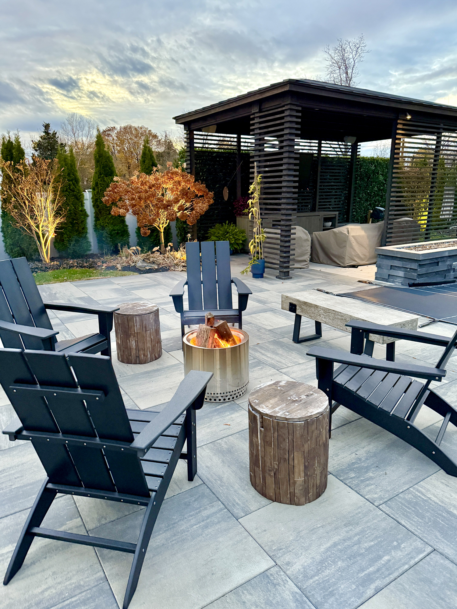 outdoor sitting area fire pit in a chilly new york backyard in the fall. enjoy landscaping, foliage and beauty while staying warm and cozy. perfect for solo, friends and family entertaining outside.