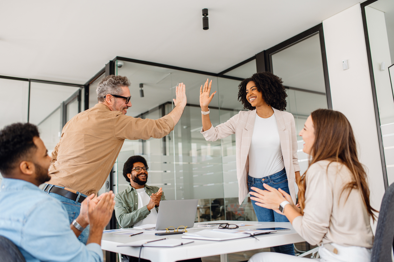 a diverse group of professionals in a modern office celebrates success with a high five