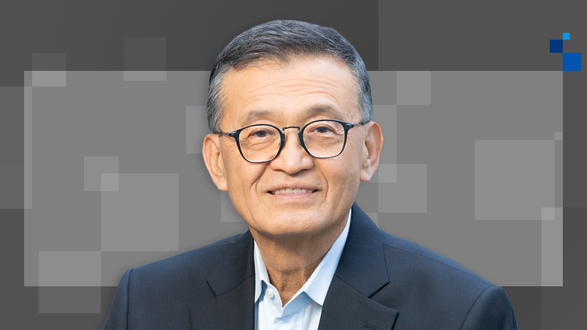Intel CEO Lip-Bu Tan, wearing glasses and a navy suit, smiling against a geometric gray background.