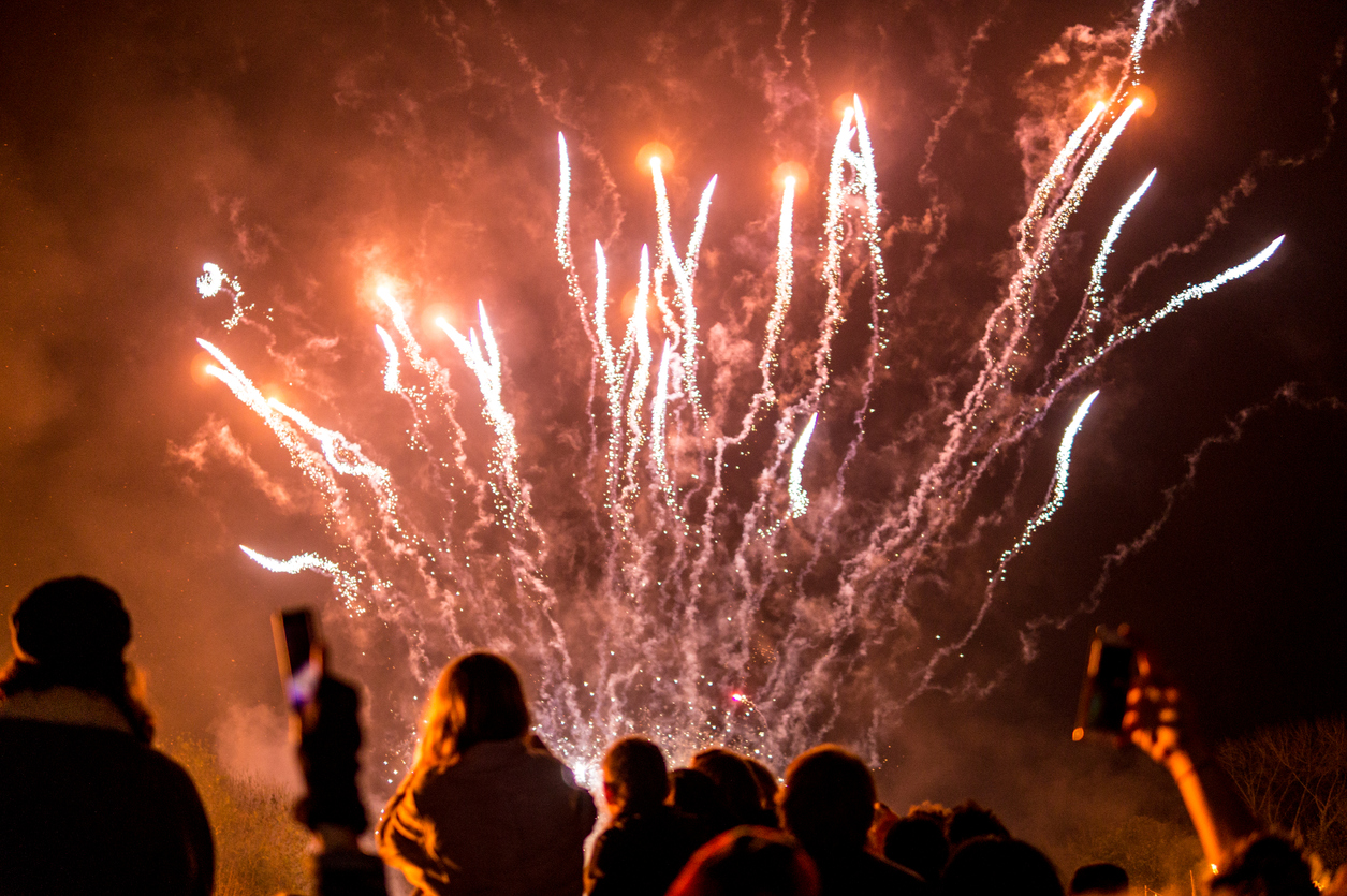 people looking at firework display against sky at night