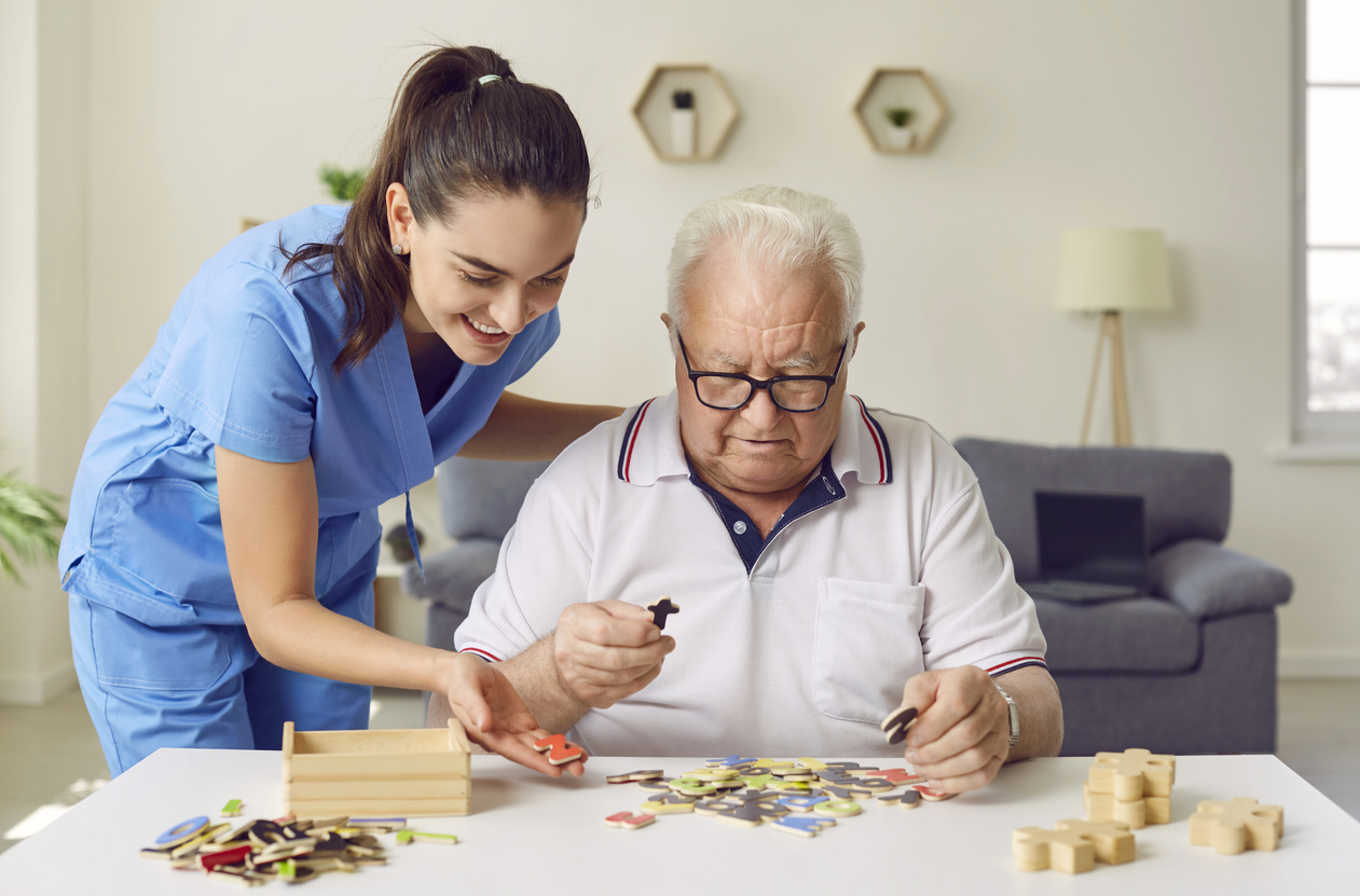 nurse in retirement home is helping demented senior patient with puzzle activity