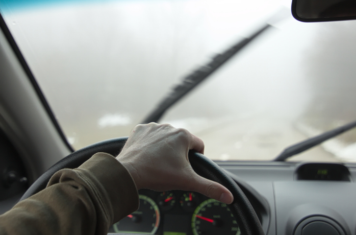 cropped hand of car&acute;s driver in bad foggy conditions