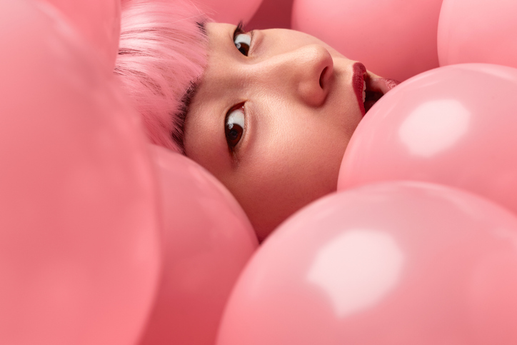 face of amazed asian woman in pink balloons