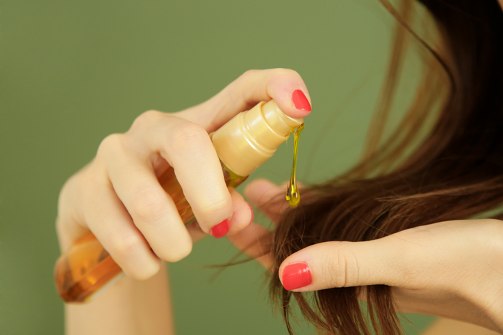 woman applying oil on hair ends, split hair tips, dry hair or sun protection concept