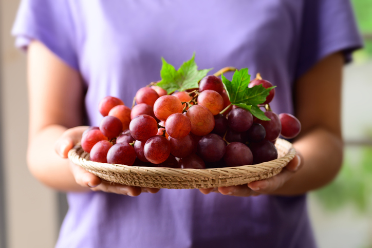 red grapes fruit holding by woman hand