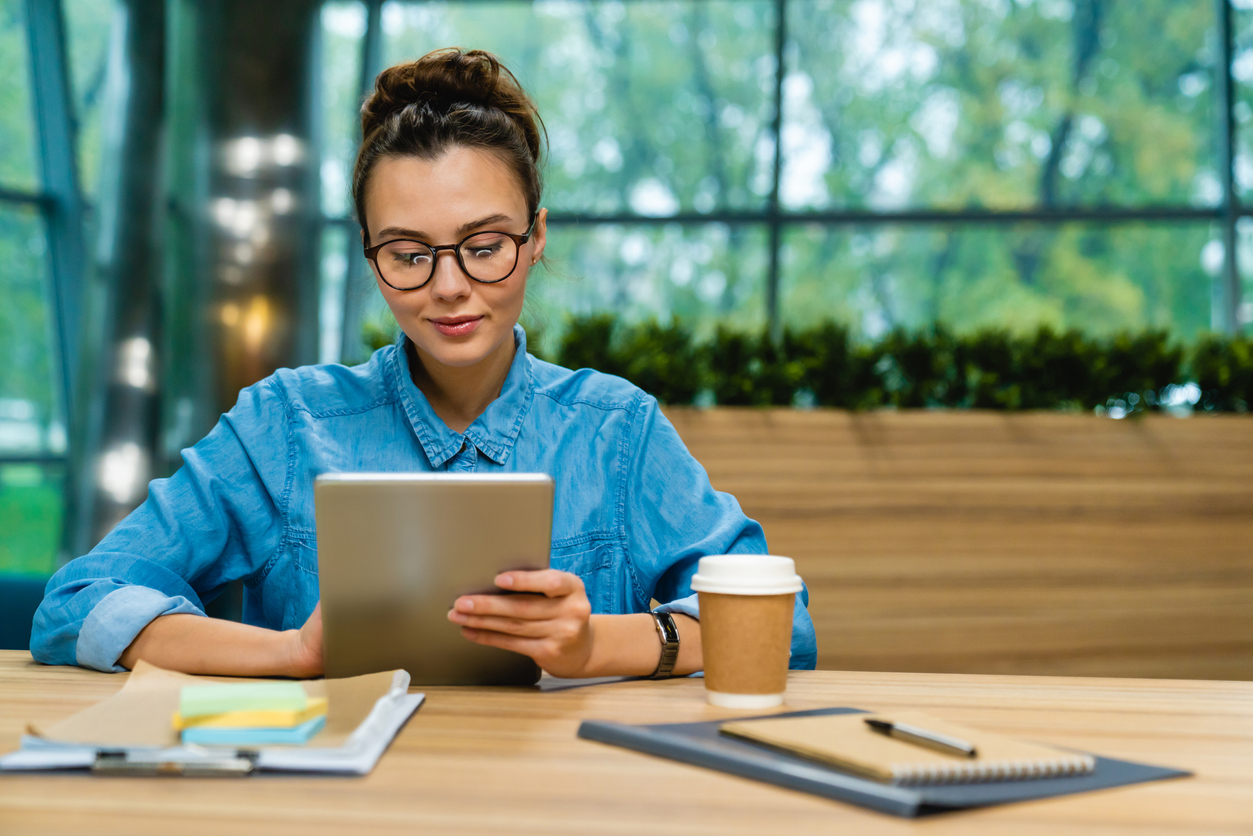 nice looking young caucasian businesswoman using tablet at the desk in modern office