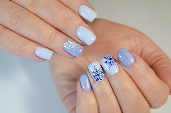 the hand of a young woman with a blue manicure and design for the new year and christmas.