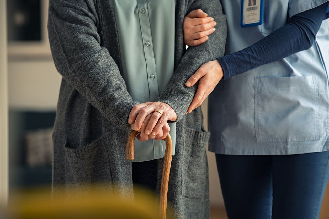 nurse assisting senior with walking cane
