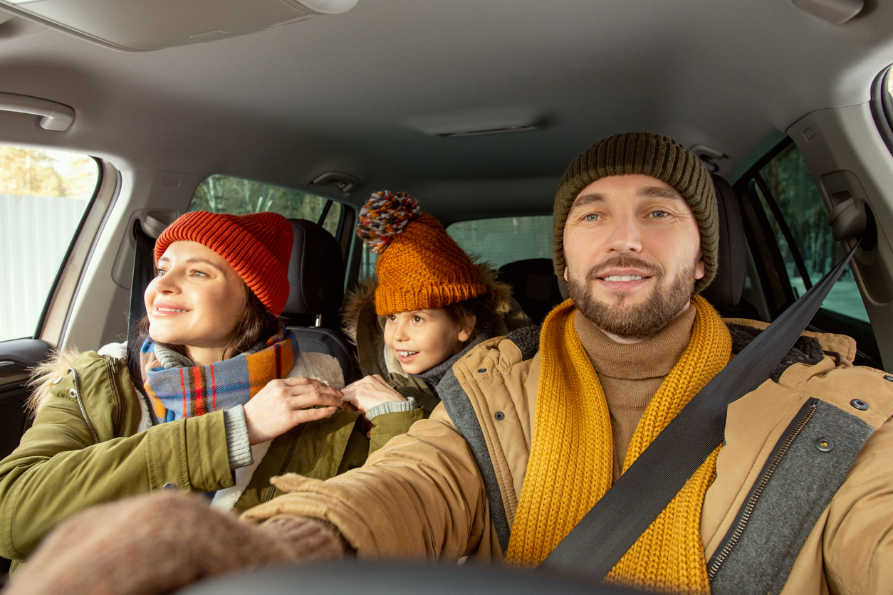 happy young active man in warm winterwear looking through front window of car