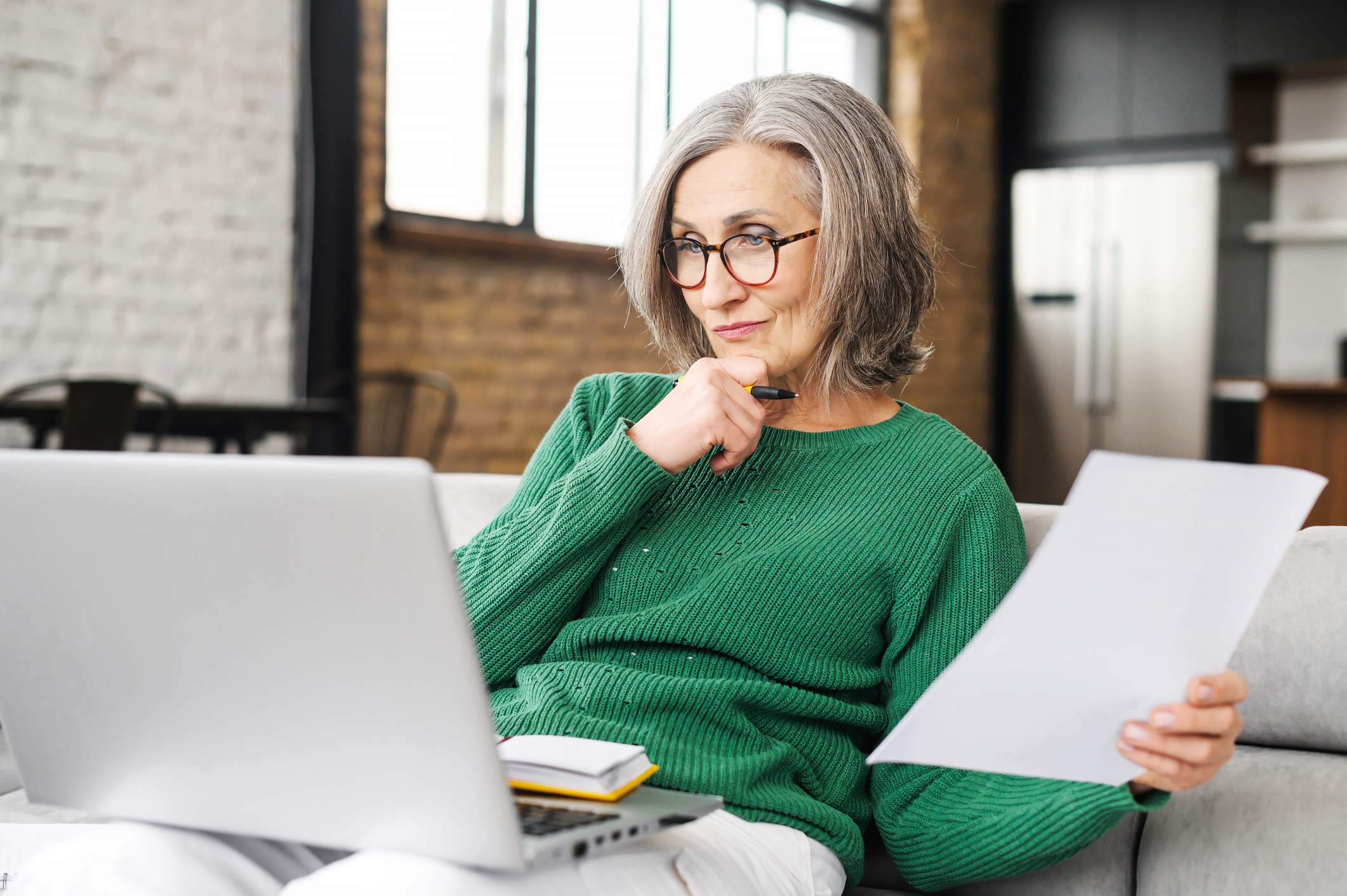 serious senior accountant sitting on the living room and looking at the laptop