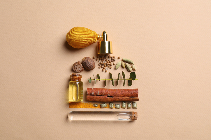 bottle of luxury perfume and different ingredients on beige background, flat lay