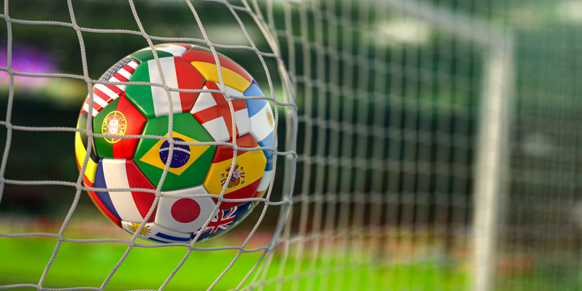 football ball with flags of world countries in the net of goal of football stadium. world cup championship 2022.