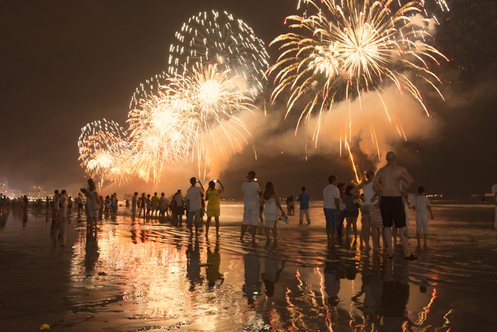 new year's celebration on the beach. people watching the fireworks at the water's edge.